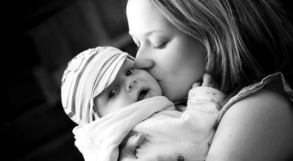 Madre abrazando y besando a su hija en brazos