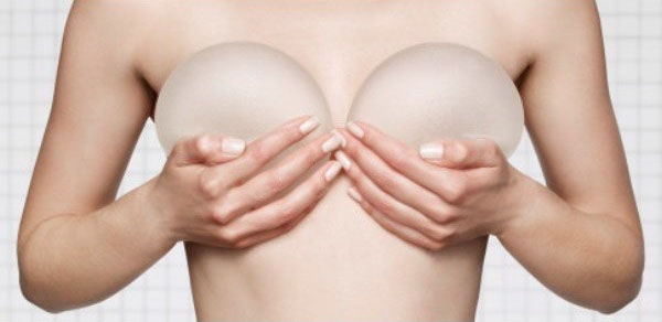 Mujer sosteniendo implantes mamarios sobre su pecho