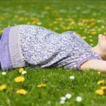 Mujer embarazada en el pasto con flores