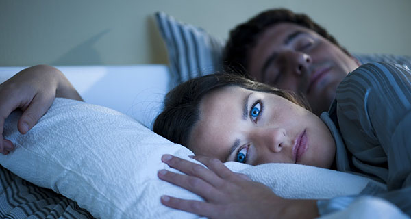 Mujer joven con insomnio en la cama con marido
