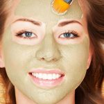 Mujer feliz con máscara facial con arcilla Tierra Madre