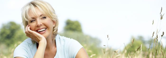 Mujer de 50 años feliz sonriendo en un campo verde