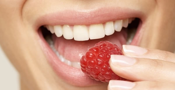 Dientes saludables mordiendo una frutilla